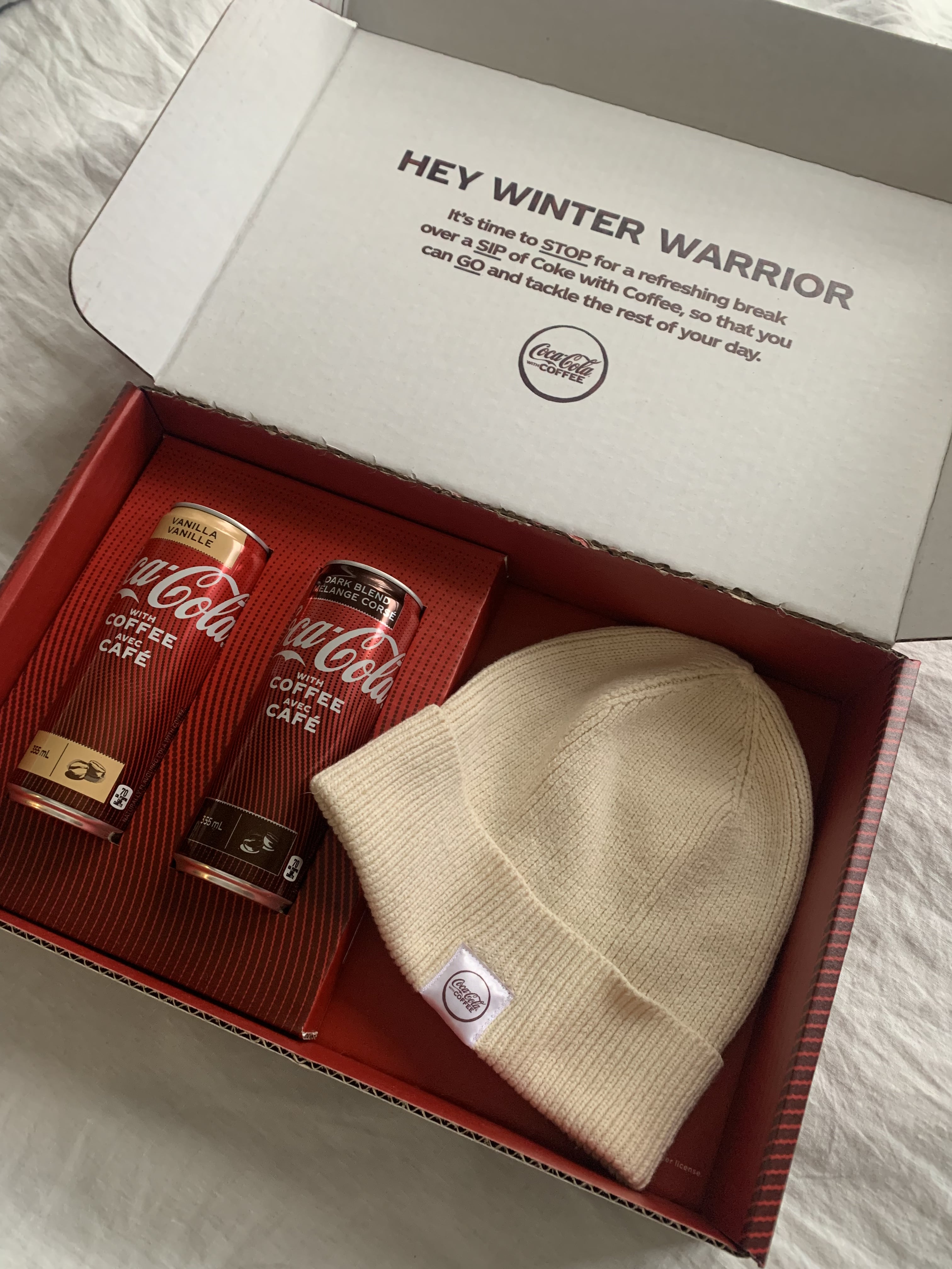 Merchandise box with cans of Coke and a toque